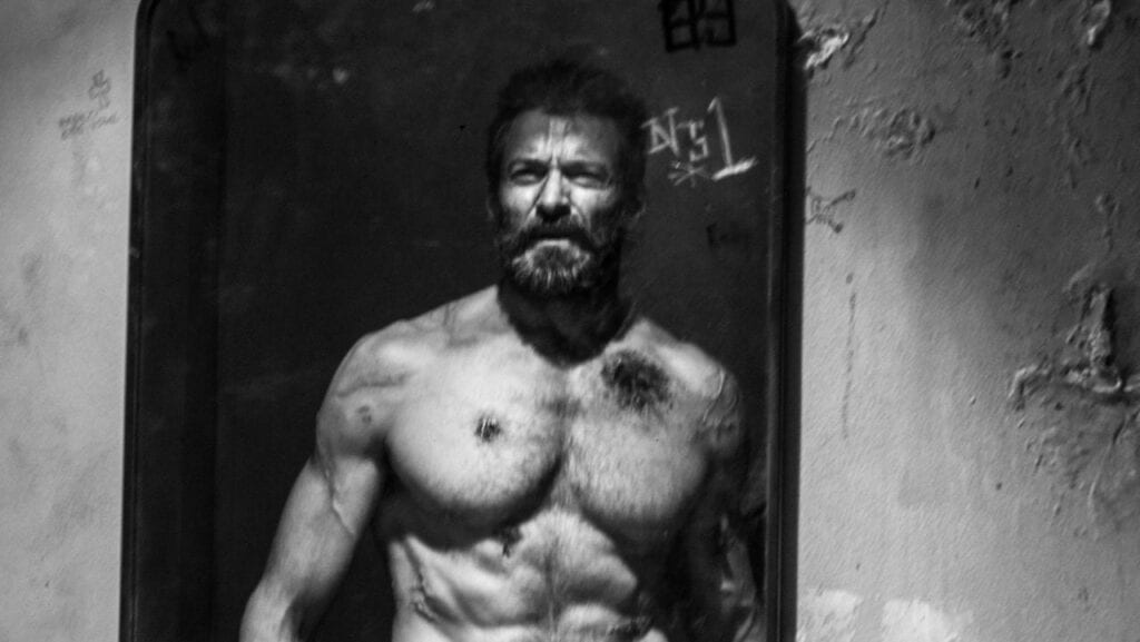 Hugh jackman looks into a mirror as Logan